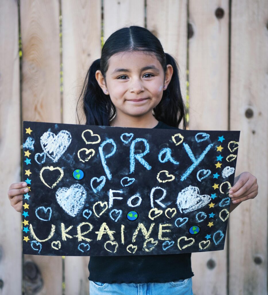 Young girl holding a 'Pray for Ukraine' sign, promoting peace.
